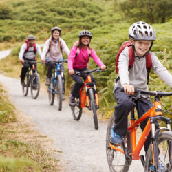Pre-teen boy riding mountain bike with his sister and parents during a family camping trip, close up